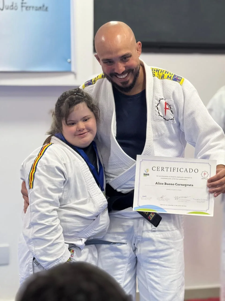 Professor e judoca celebrando a entrega de um certificado no Judô Ferrante
