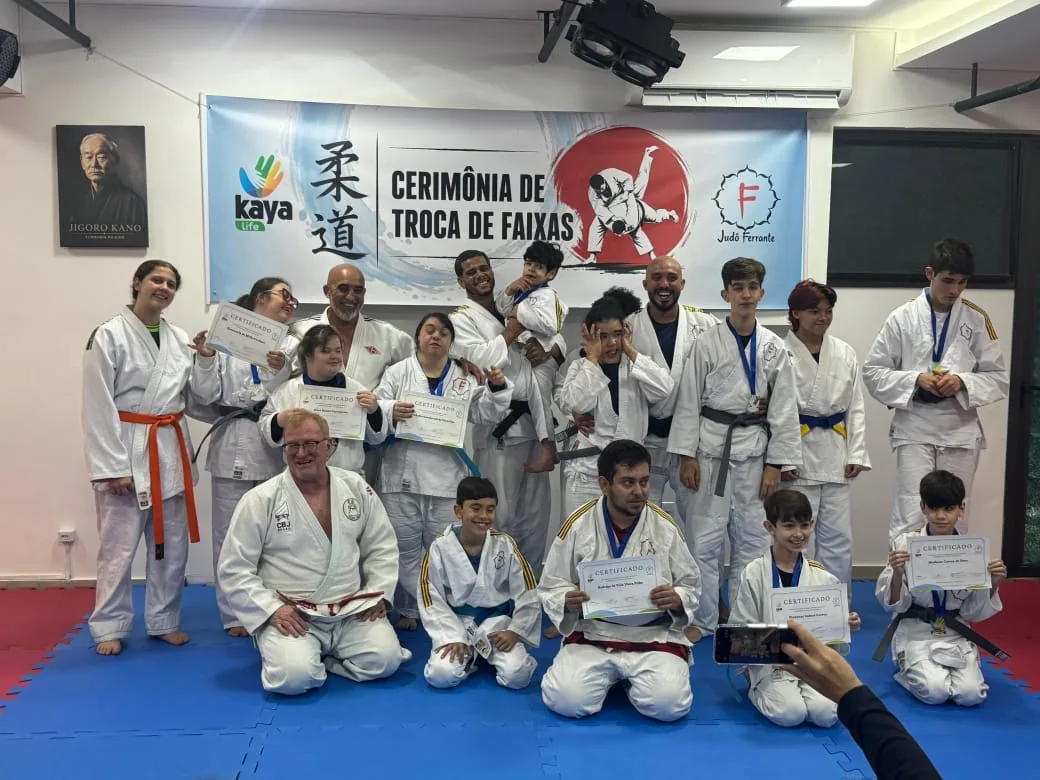 Foto real da equipe e dos judocas reunidos em cerimônia inclusiva de troca de faixas e entrega de certificados